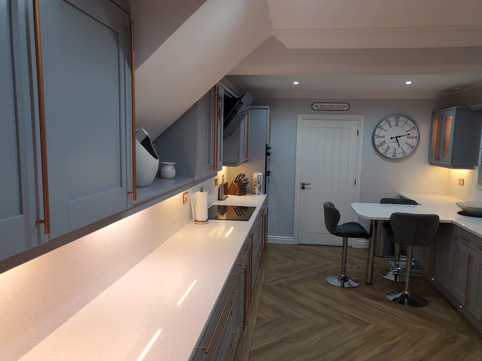 Arctic Starburst quartz running the length of a grey shaker kitchen, with the breakfast bar and stools at the far end