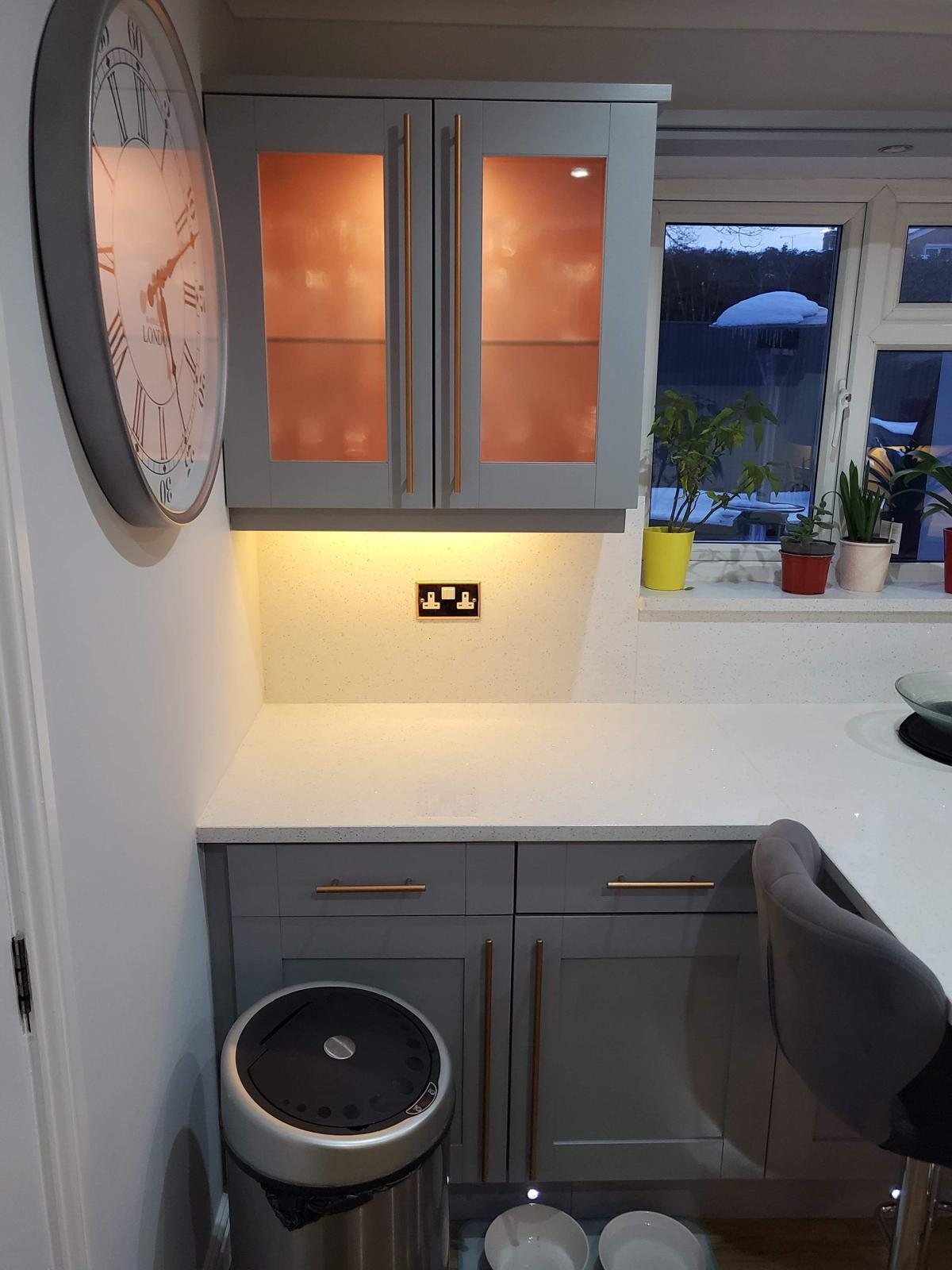 Corner of an Arctic Starburst worktop below glazed wall units, the white sparkle catching the under-cabinet lighting