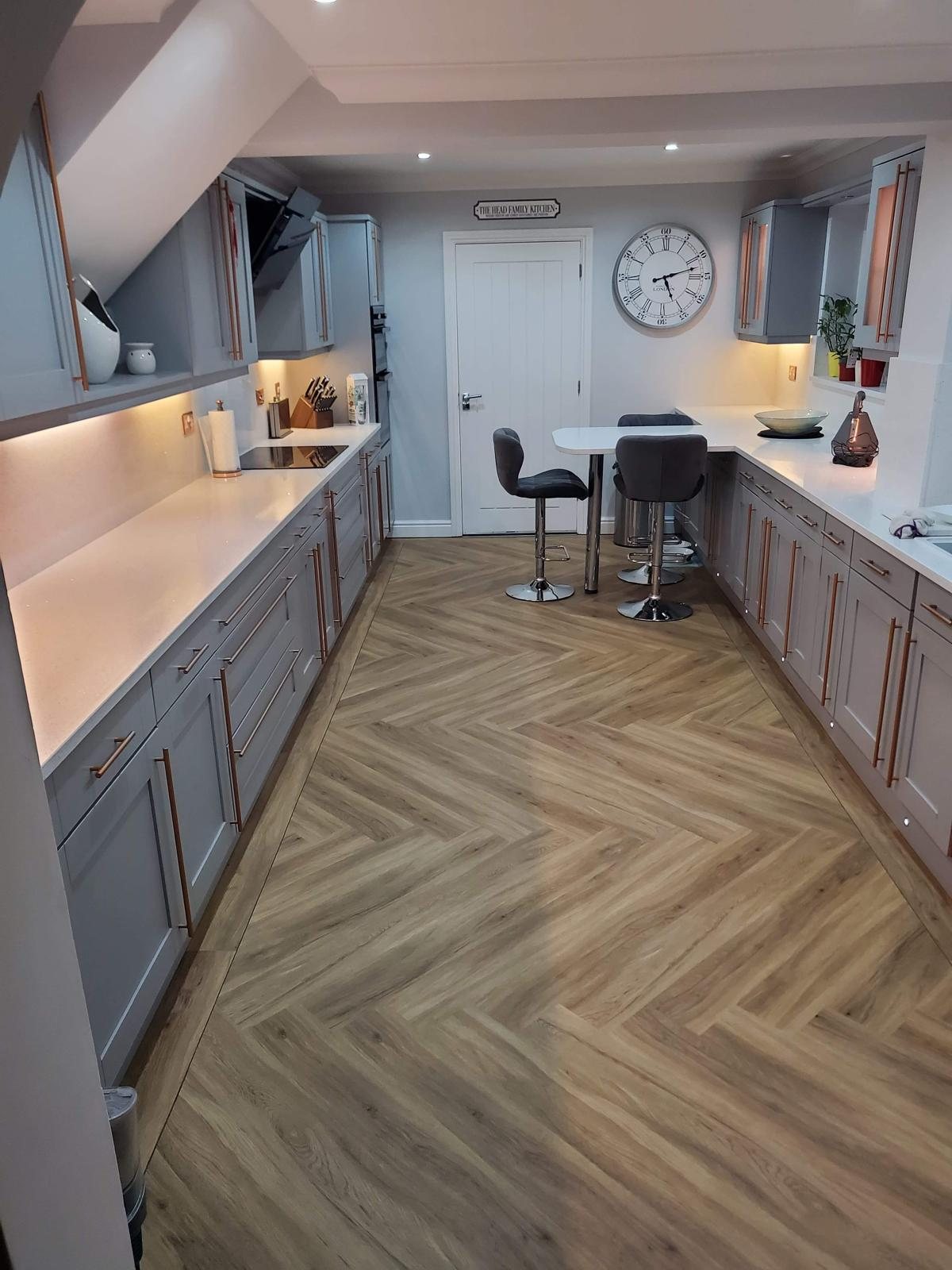 Galley kitchen in grey shaker units with Arctic Starburst worktops down both runs and a herringbone floor