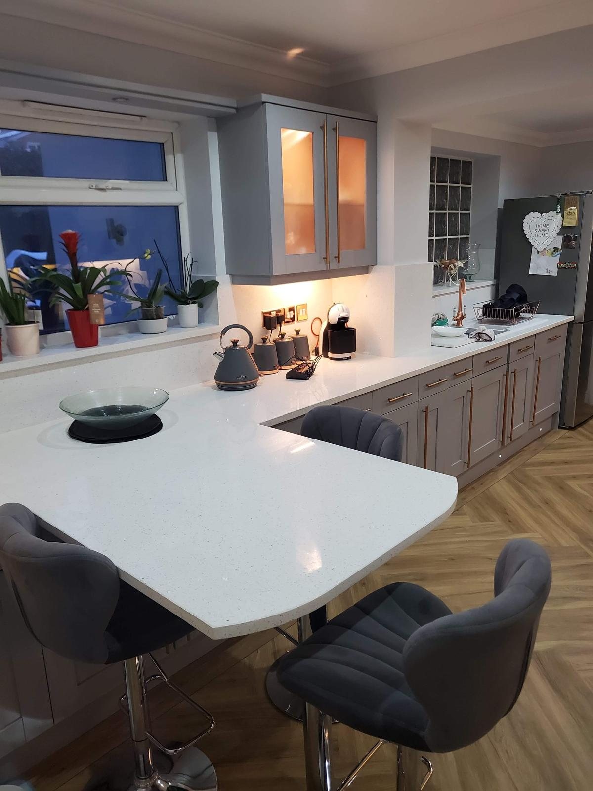 Rounded Arctic Starburst breakfast bar with dark grey stools tucked under the overhang
