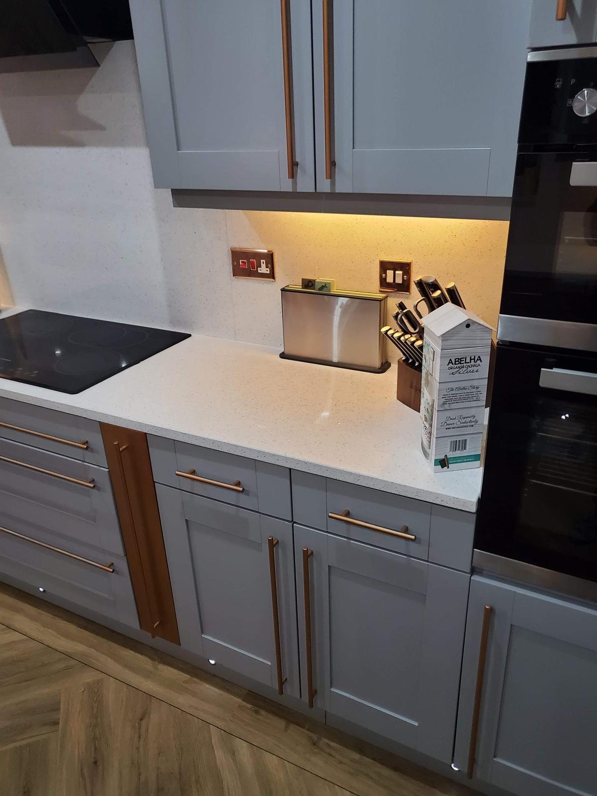 Induction hob set into Arctic Starburst beside the oven housing in grey shaker units
