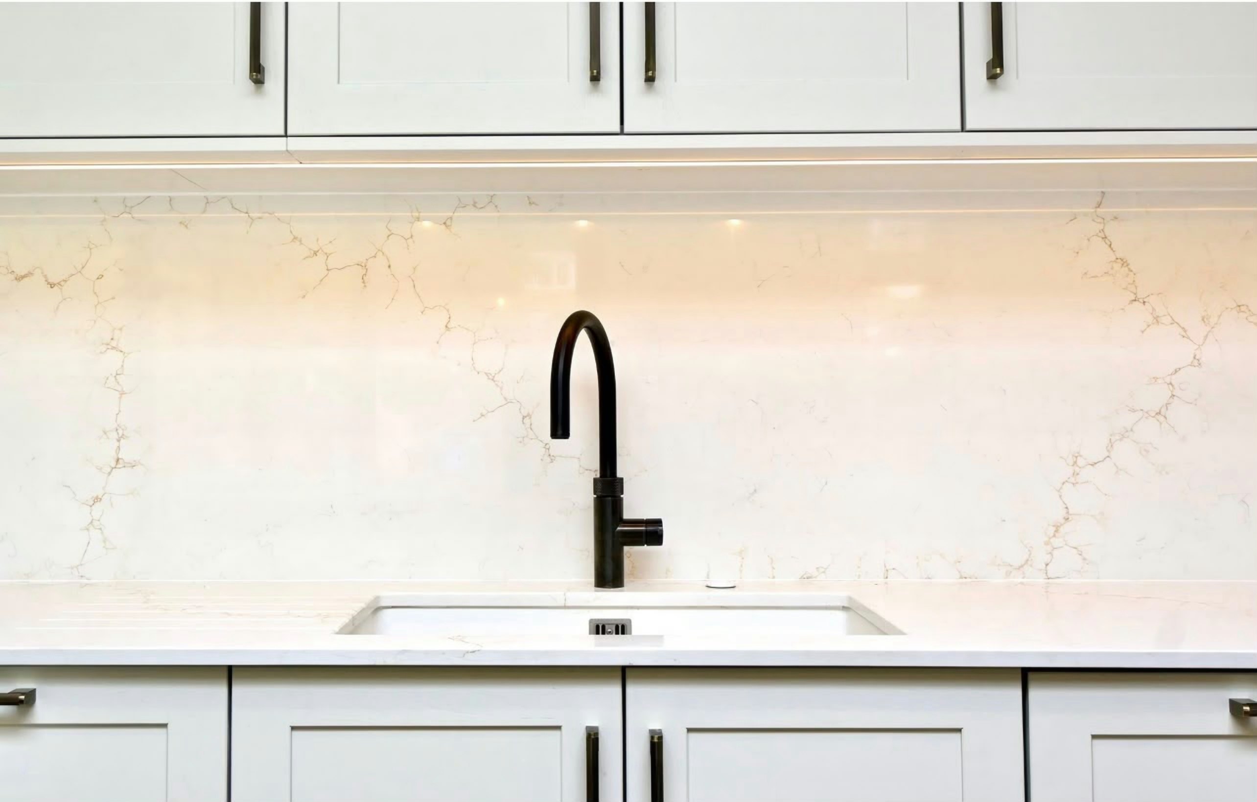 Black tap and undermount sink below an Aurora Gold splashback, the fine gold veining running across the full panel