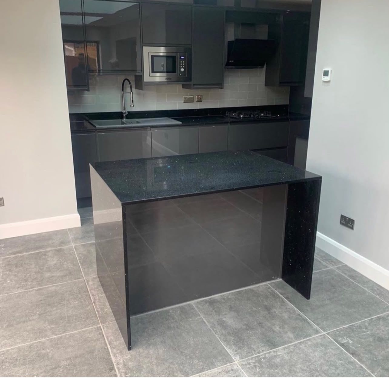 Black Sparkle peninsula with a full-height mitred end, in a newly built kitchen