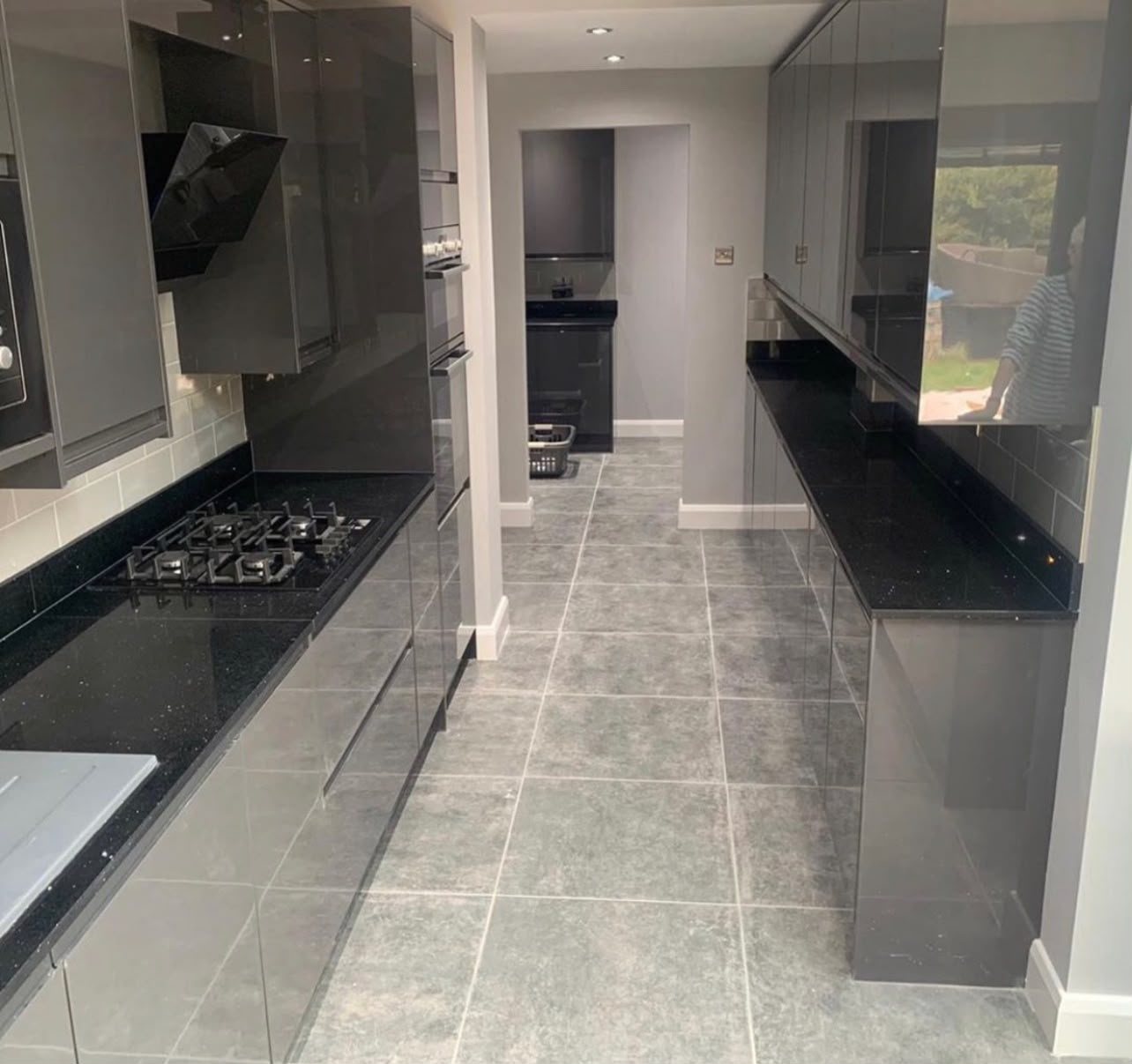 Black Sparkle worktops down both sides of a galley kitchen, the gas hob on the left run