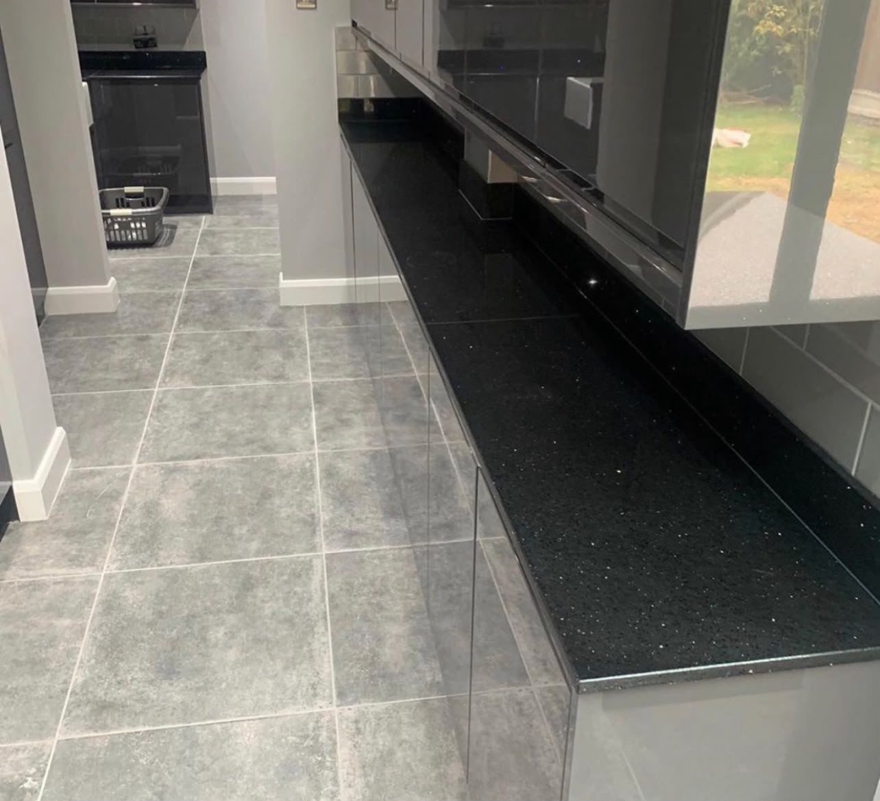 Long Black Sparkle run catching the light along a grey tiled kitchen floor