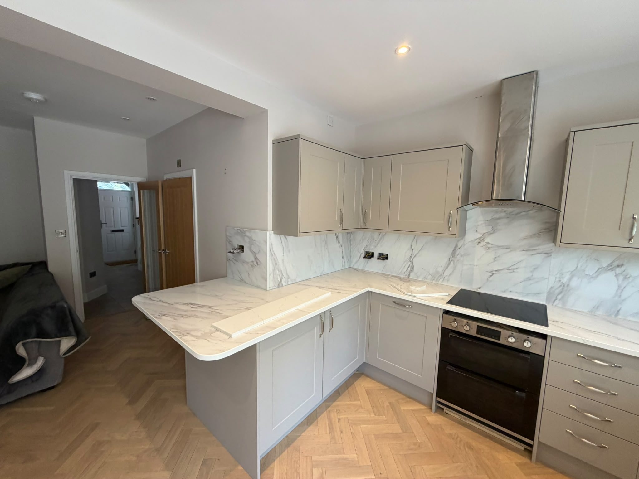 U-shaped taupe kitchen with Calacatta Glacier worktops, photographed mid-fit with the room still unfinished