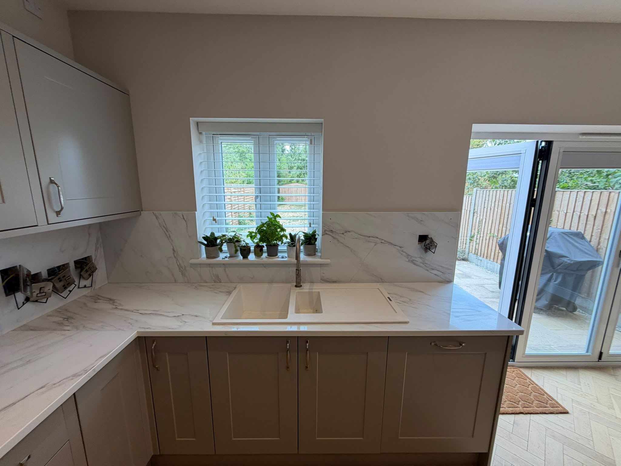 Undermount sink in a Calacatta Glacier worktop below the window, with herbs on the sill