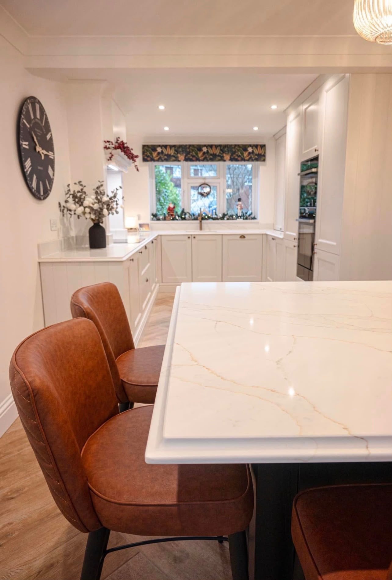 Calacatta Gold island with tan leather stools along one side