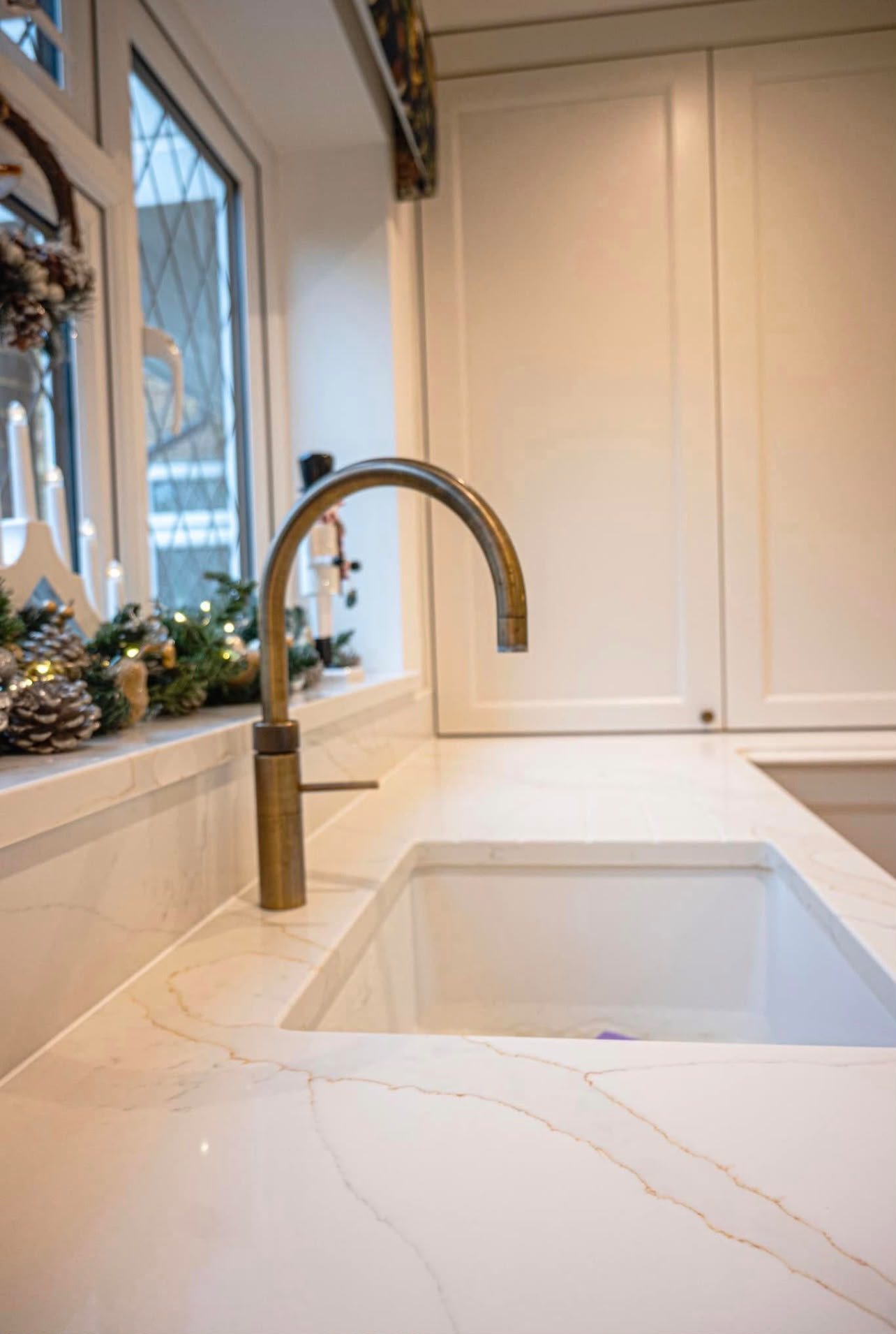 Undermount sink in Calacatta Gold with a brushed brass tap above it