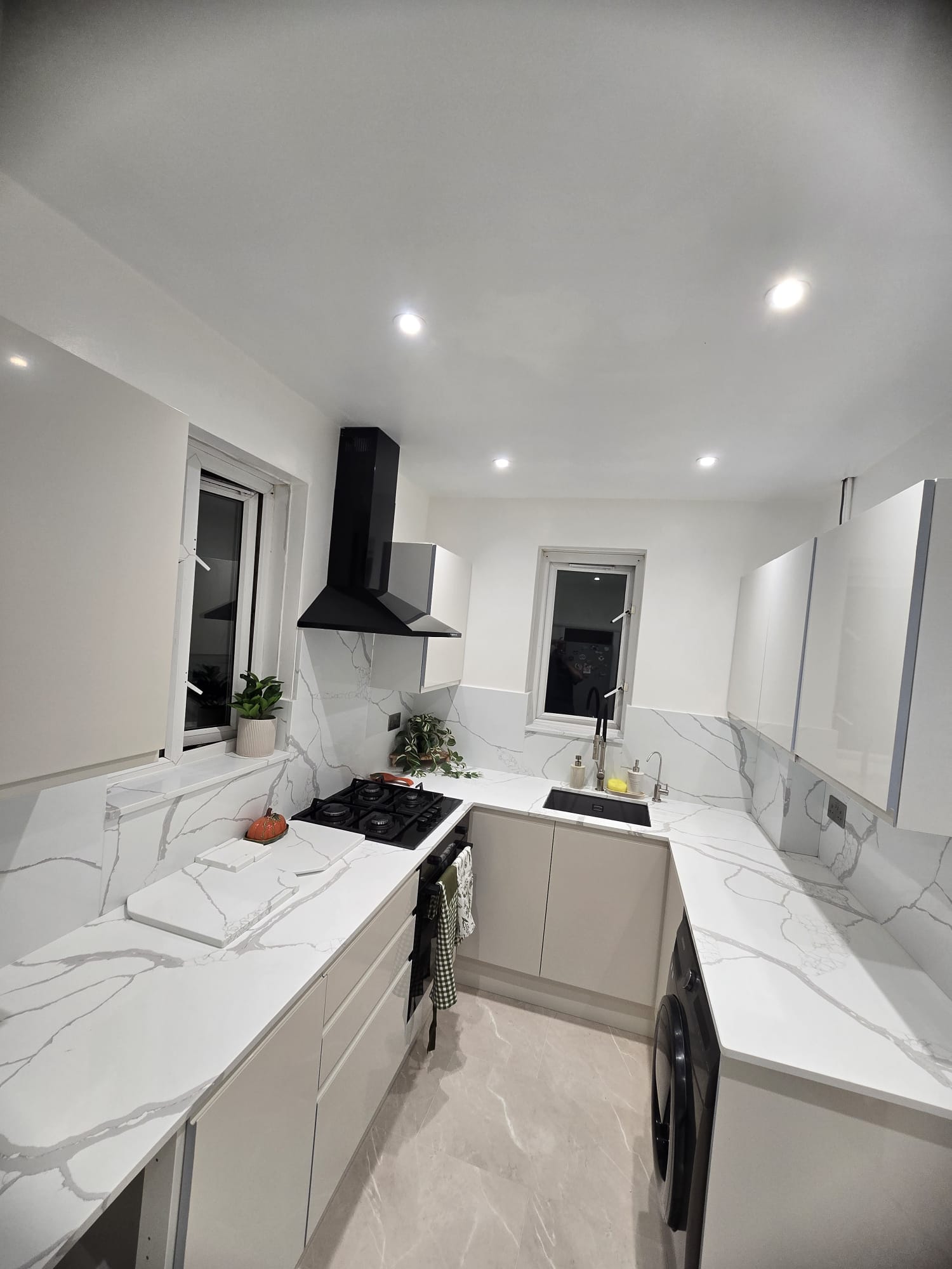 Small U-shaped kitchen in stone grey, Calacatta Venato worktops and full-height splashback carried round all three walls