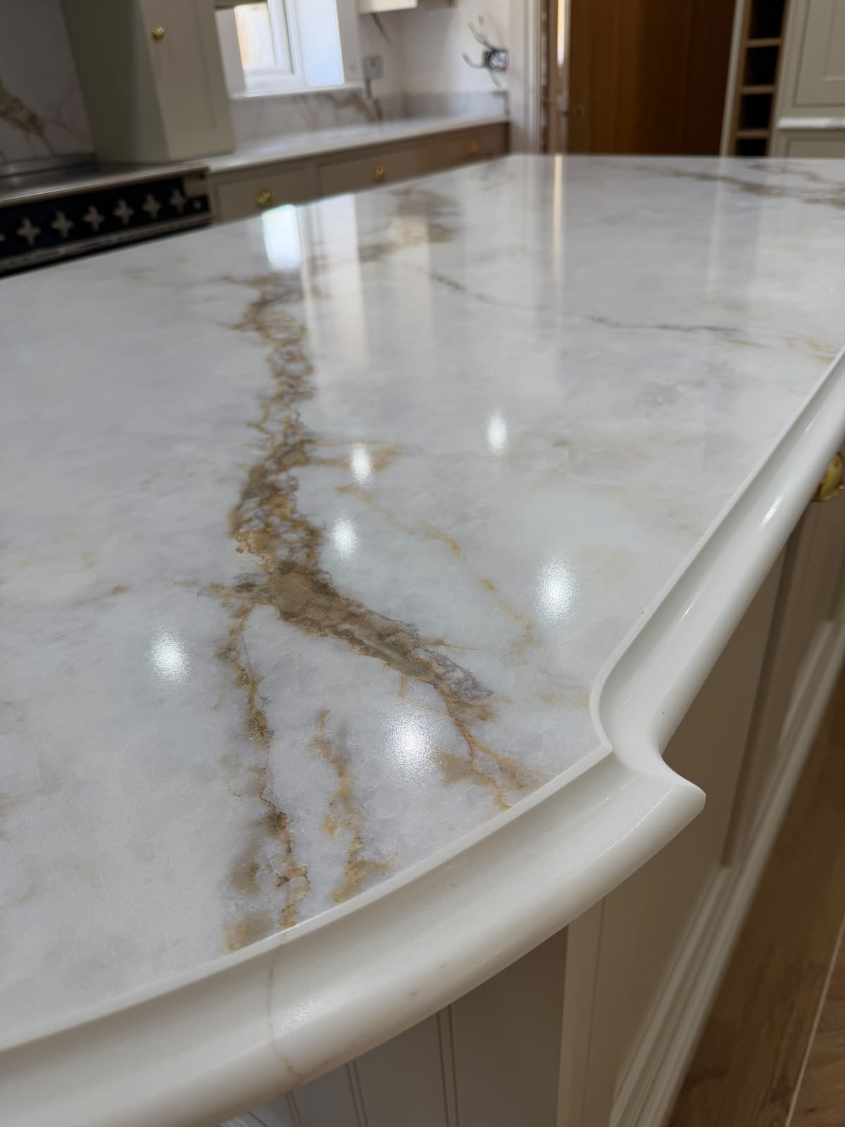 Shaped edge on a Golden Calacatta island, the gold vein carried across the curve