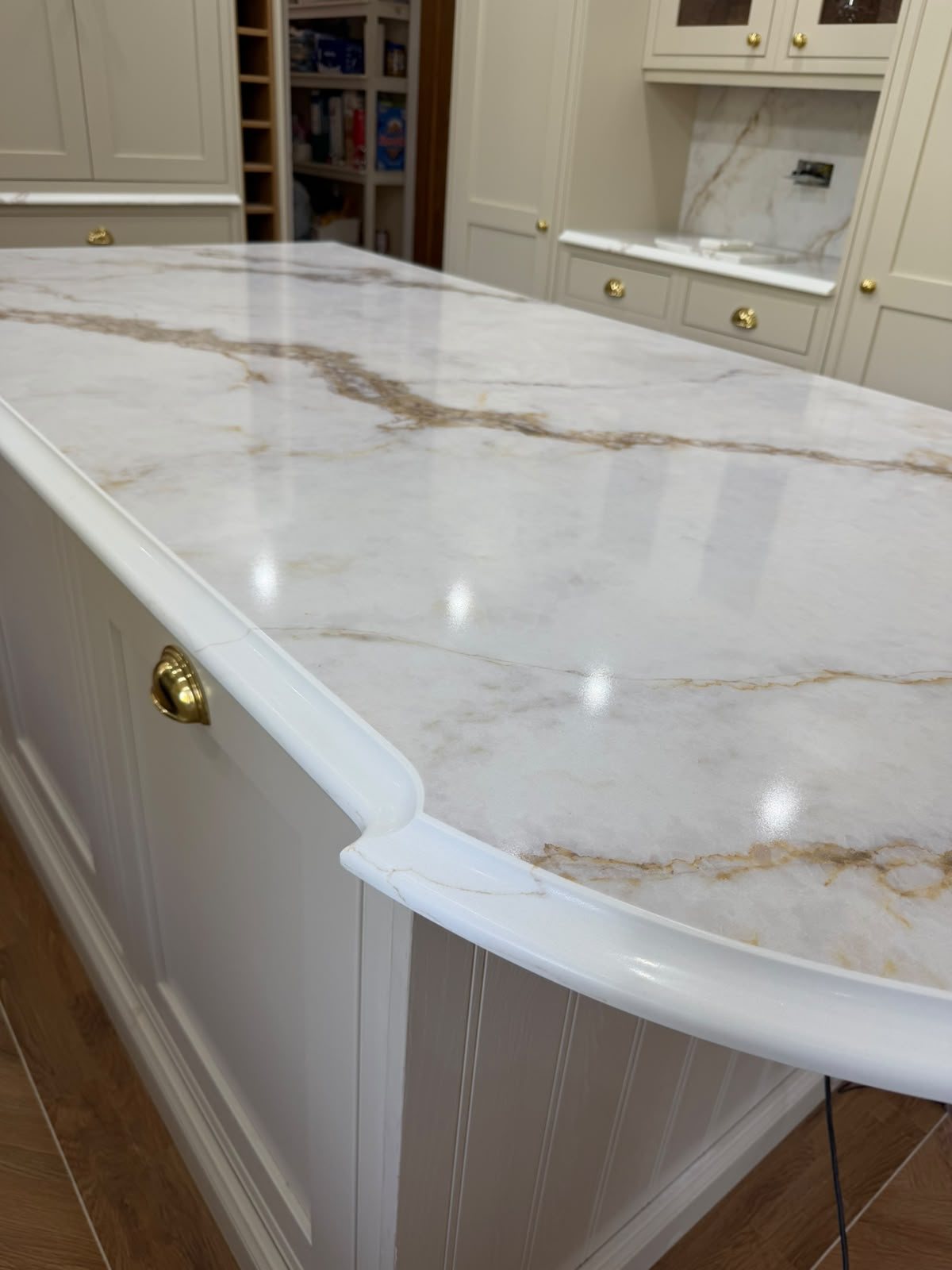 Golden Calacatta island with a curved end and a brass handle below it