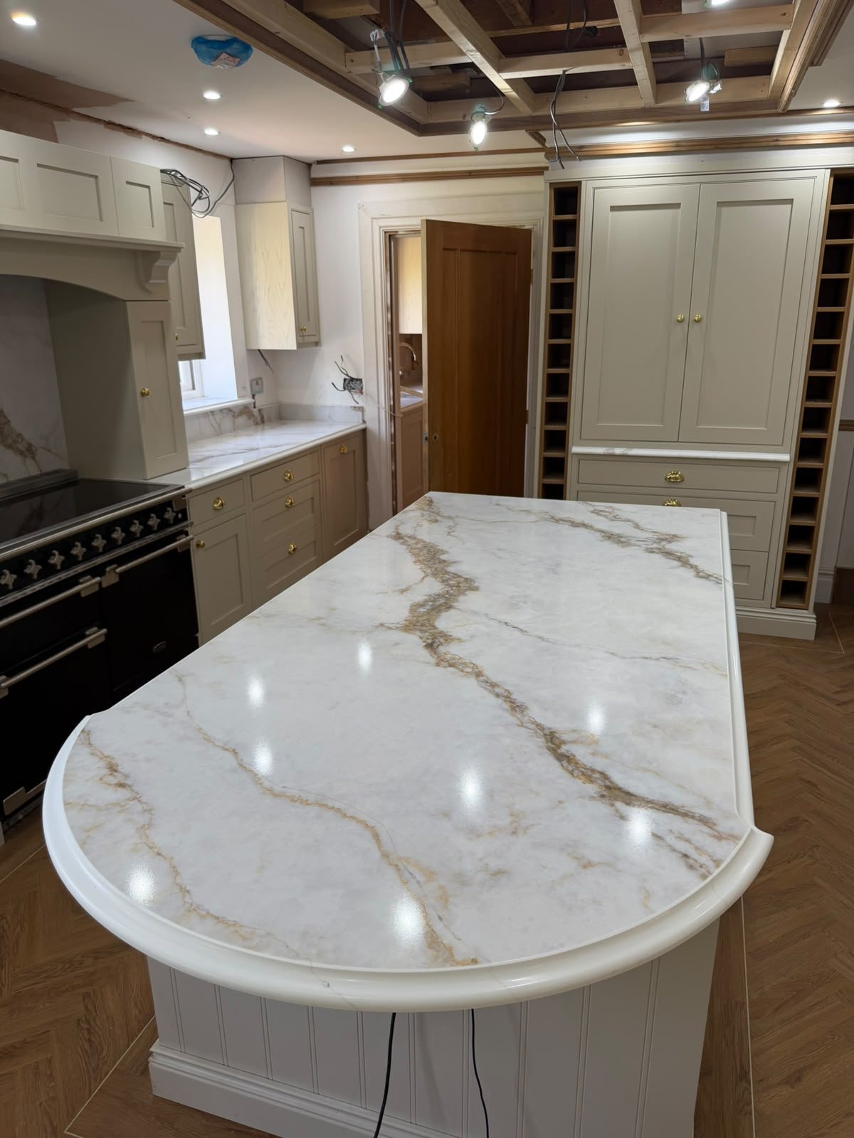 Golden Calacatta island in a cream in-frame kitchen, with the black range cooker behind it