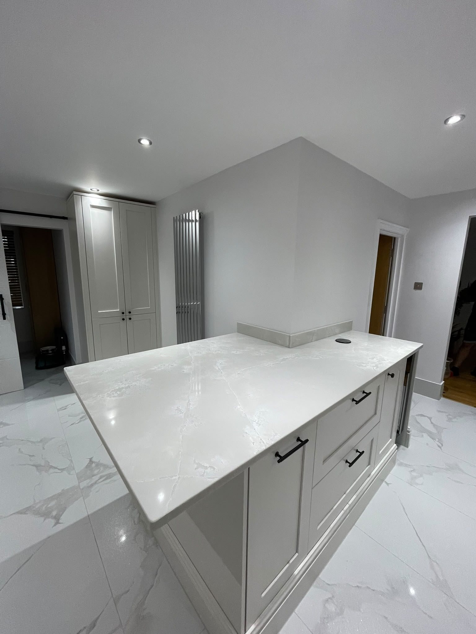 Polar White peninsula in a white in-frame kitchen, on a marble-effect tiled floor