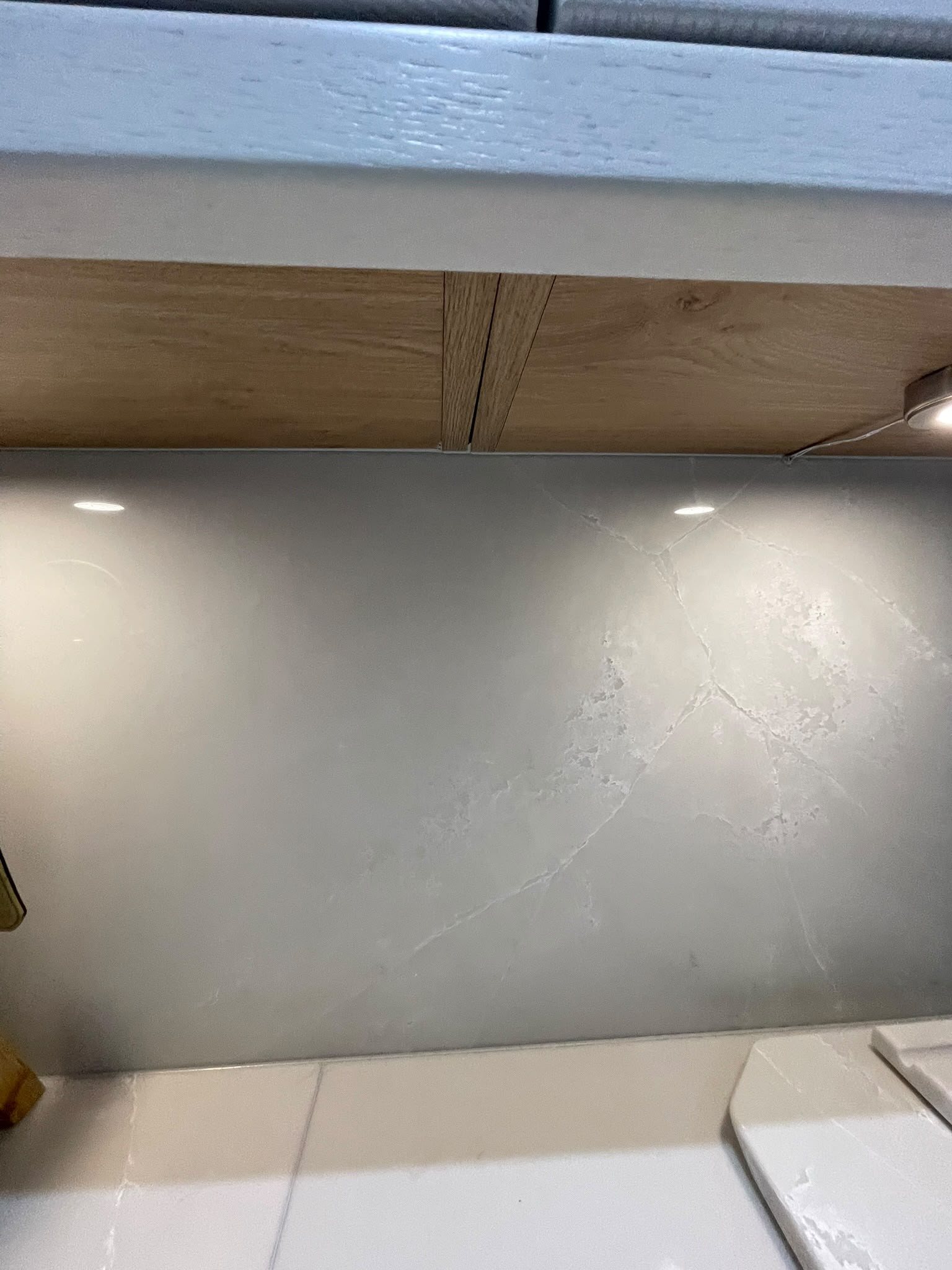 Veined grey splashback panel under oak wall units, the Polar White worktop and a chopping board along the bottom of the frame