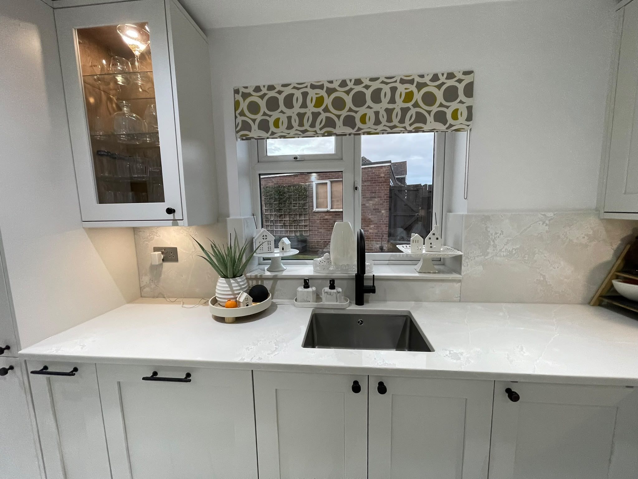 Undermount sink in a Polar White worktop below the window, with a black tap