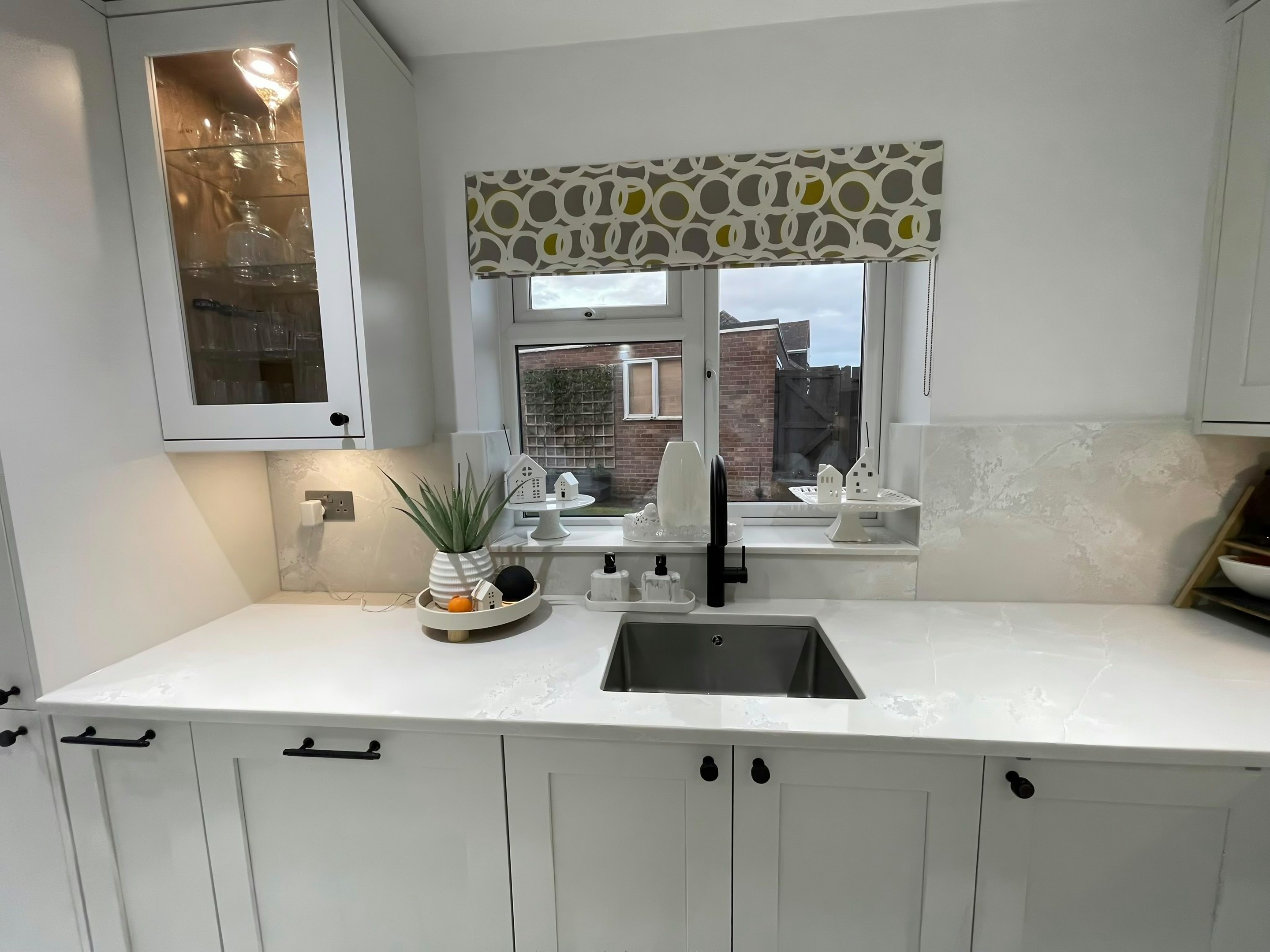 Undermount sink in a Polar White worktop below the window, with a black tap