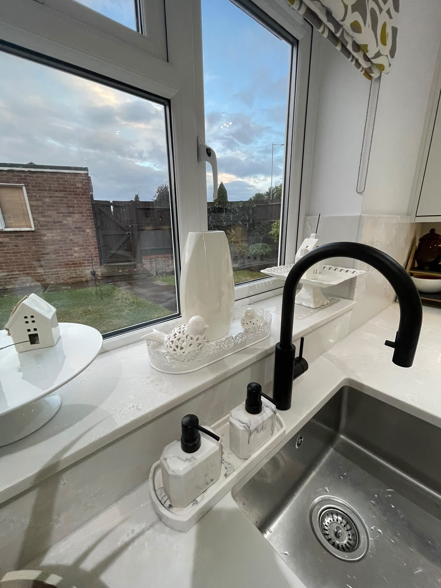 Black tap and undermount sink set into Polar White, the window sill above