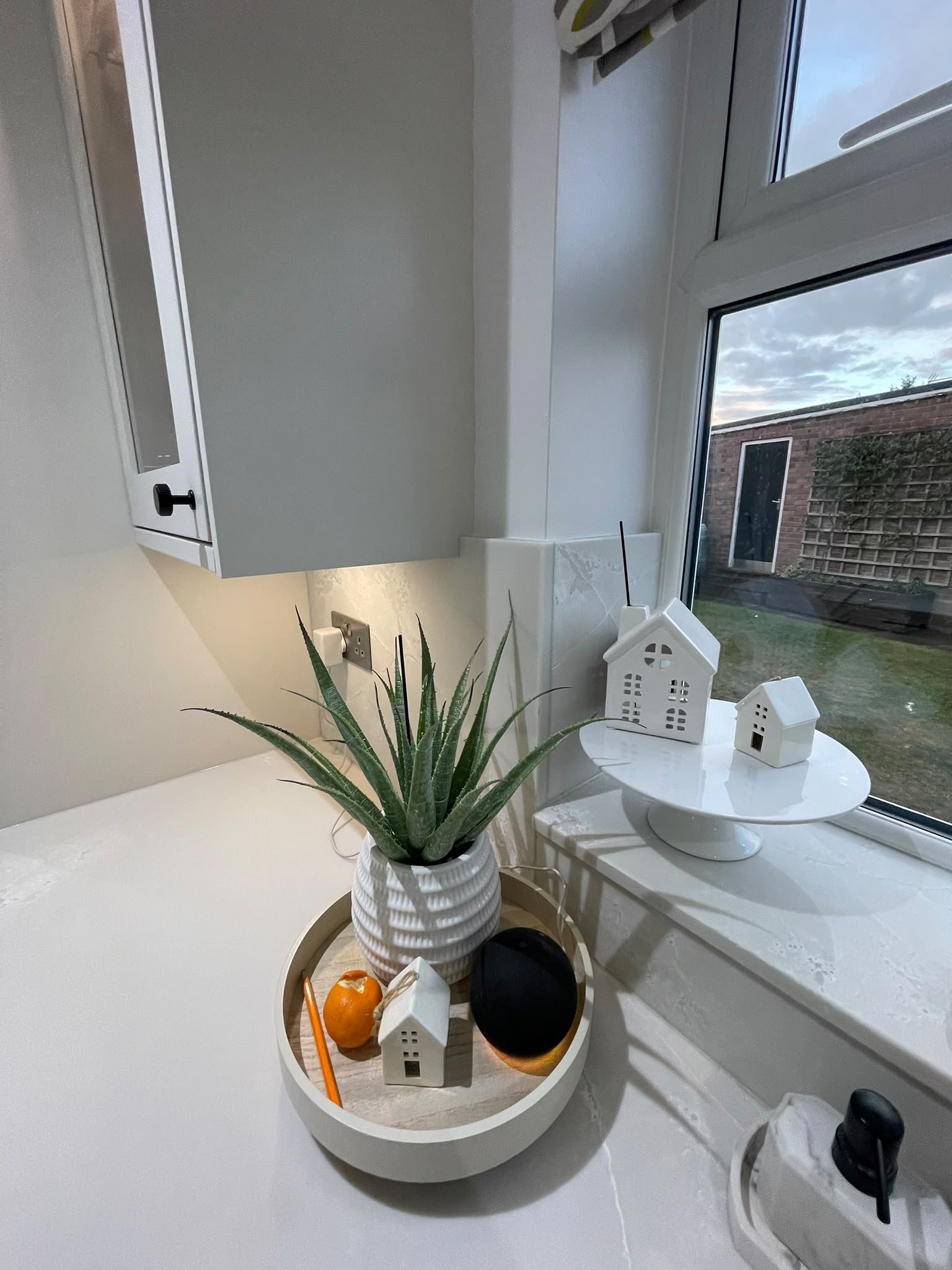 Polar White worktop below the window, with a plant and a tray on it