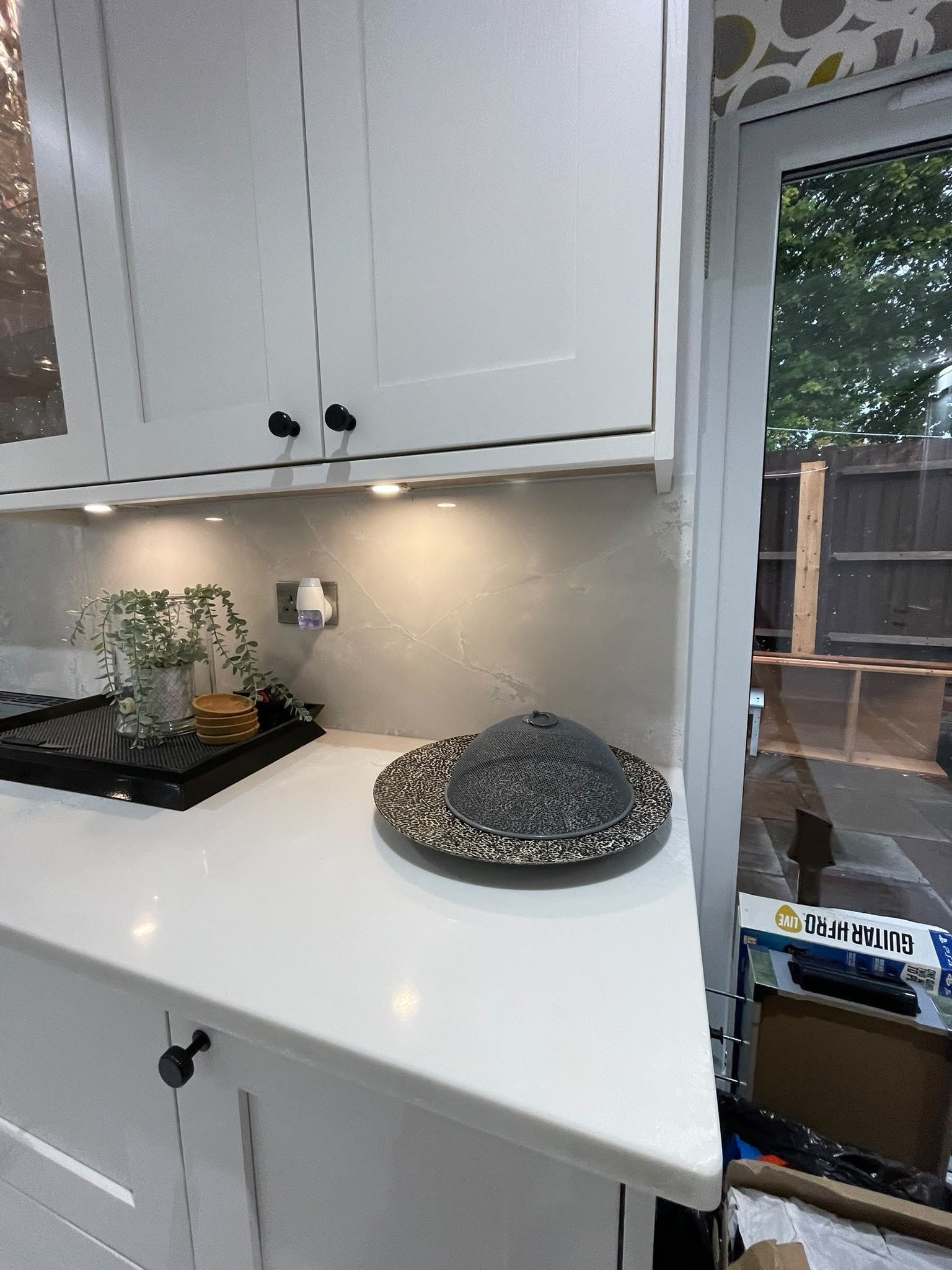 Polar White worktop running to the back door below a veined grey splashback, photographed before the kitchen was finished