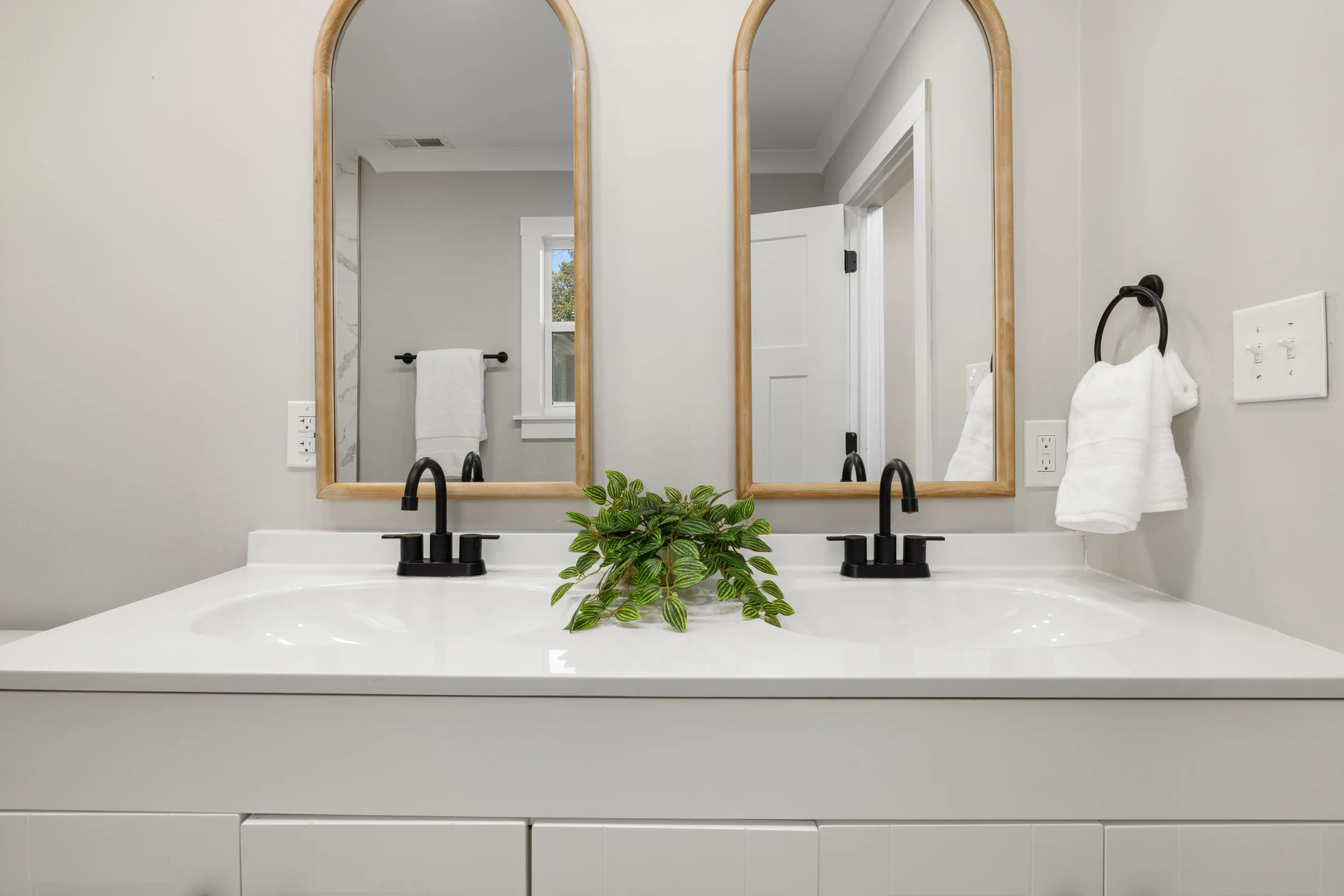 Modern bathroom vanity featuring double sinks, mirrors, and stylish black faucets.