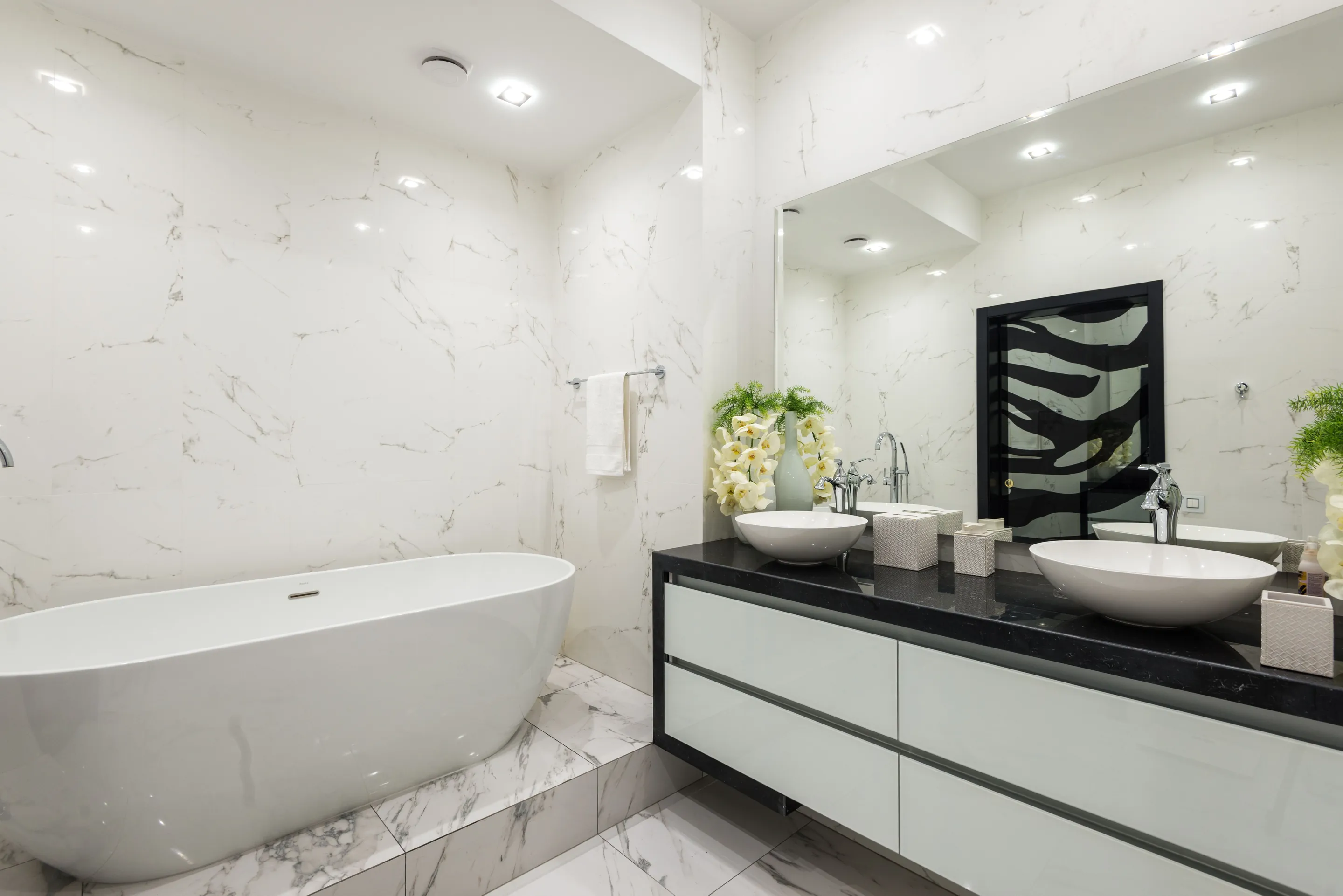 Interior of contemporary bathroom with white marble bathtub tiled walls and floor and cabinet under sink with chrome faucet