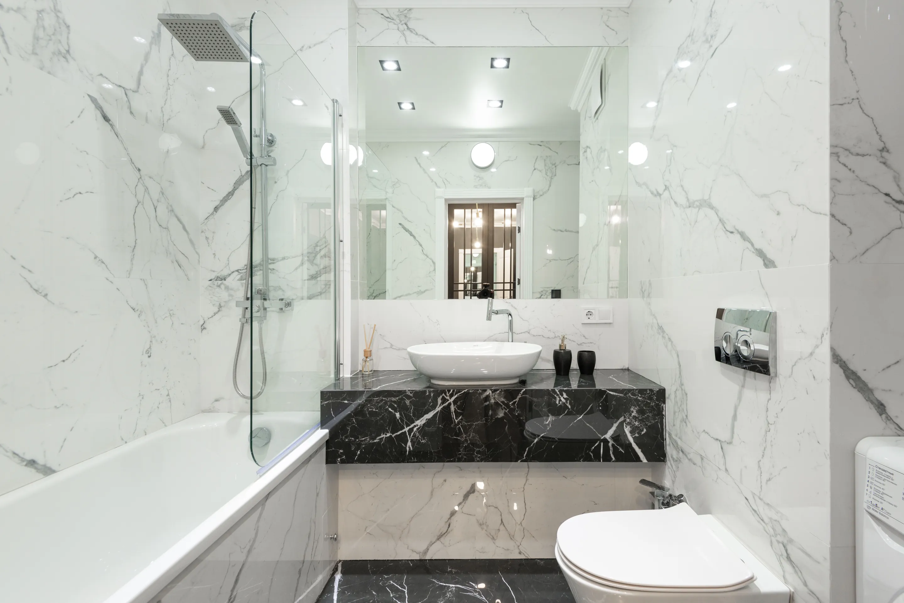 Elegant bathroom with marble decor, featuring bathtub, washbasin, and modern fixtures.